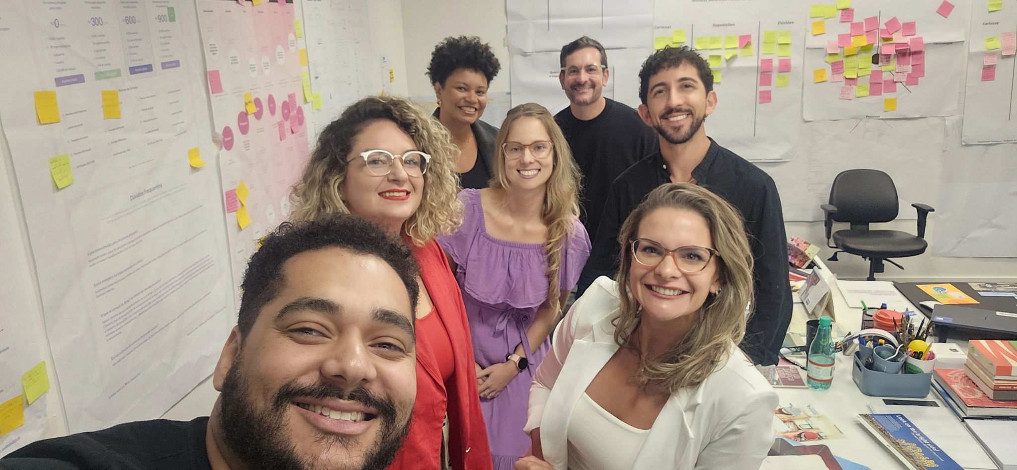Profissionais em um workshop de ABM, com quadros de post-its ao fundo